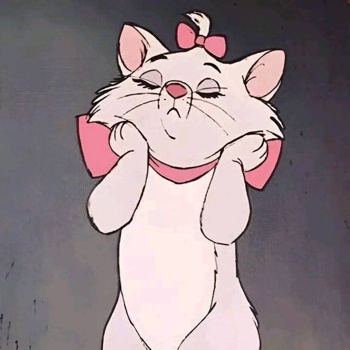 A smiling white kitten with its paws resting on its cheeks.